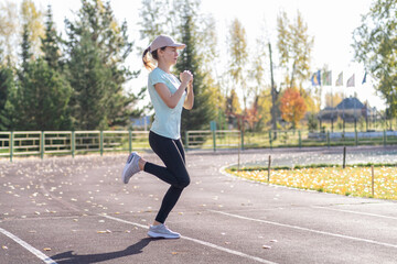 A young beautiful woman in sportswear plays sports at a local stadium. Exercise, jog and exercise at the beginning of the day. Healthy and active lifestyle.