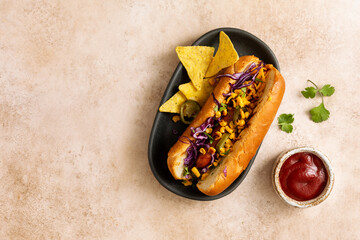 Hot dog with sweet corn, jalapenos, red cabbage, and nachos.