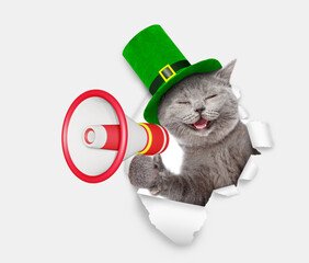 Saint Patricks Day concept. Funny cat wearing a green leprechaun hat looks through the hole in...