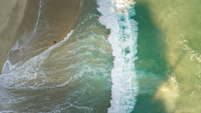California Dreaming: A Lone Surfer entering the ocean - Aerial Drone View