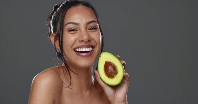Woman, avocado and beauty in studio for health, diet or smile on face for skincare by background. Girl, model or happy for fruit, nutrition choice or vegan food for wellness, natural glow or portrait
