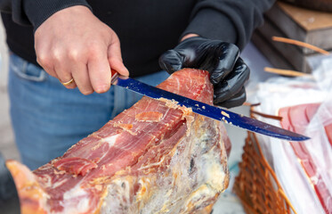 Man cut off meat jamon with a knife