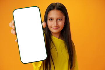 Teen girl showing smartphone screen with copy space over yellow background