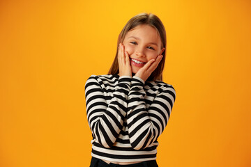 Surprised amazed teen girl against yellow background in studio