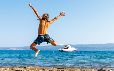 Young boy,  happy child jumping in the air on the beach- vacation, happiness, travel destination...
