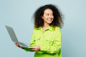 Side view smiling young IT latin woman she wear green shirt casual clothes hold use work on laptop...
