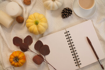 Notebook decorated with pumpkins, dried leaves and candles on a white fabric background. Vintage concept with warm autumn vibe. Enjoy the fall holiday and a happy Thanksgiving