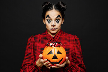 Young cool woman with Halloween makeup face art mask wears clown costume red dress hold...