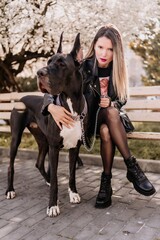 A woman walks with her Great Dane in an urban setting, enjoying the outdoors and the company of her...