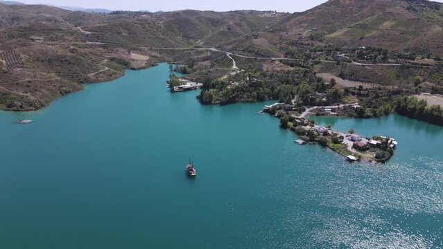Aerial view above tourist boat sailing in the shimmering turquoise waters of Green lake in the Taurus mountains of Turkey
