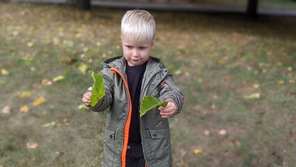 cute funny boy child blond on the street in the park