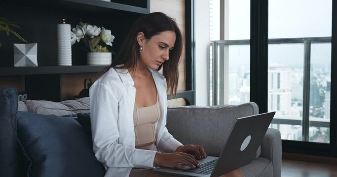 Business woman sitting on the sofa, alone in the office, typing text on a laptop. An idea came up and ways to implement it. Working atmosphere workplace idea came up concept