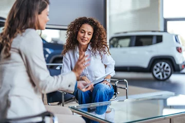 Foto op Aluminium Saleswoman and a female customer in a car dealership. Sales manager explaining looking at clipboard and explaining the car features to woman customer in showroom. © Dragana Gordic