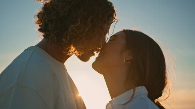 Young pair kiss at sunset ocean coast close up. Happy couple romantic evening