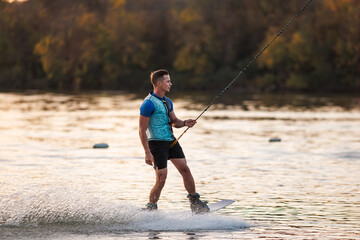 An athlete performs a trick on the water. Park at sunset. Wakeboard rider