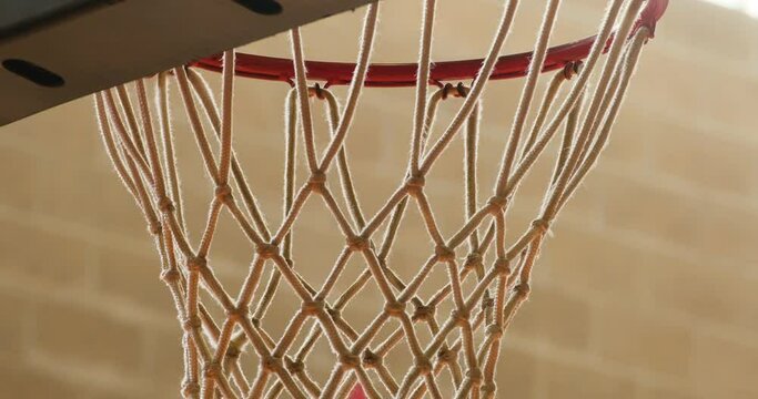 close-up of a basketball hoop with a sudden perfect basketball throw through the hoop for a swish
