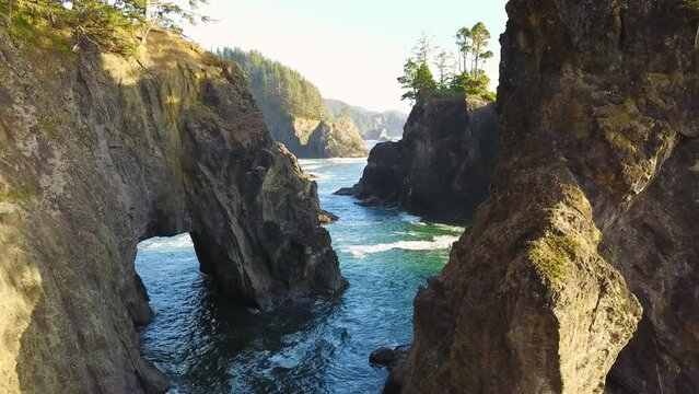 Oregon Coast Highway 101 Viewpoint of "Natural Bridge" Island rock formations. 4K Aerial drone looking down from above, waves crashing, forming natural arches in the rocky cliffs.