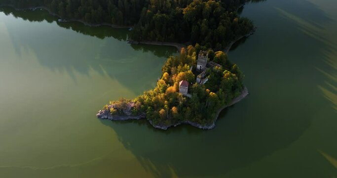 High angle aerial orbit of Ottenstein castle on peninsula point, long shadows trace on water
