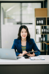 Young beautiful woman typing on tablet and laptop while sitting at the working white table office