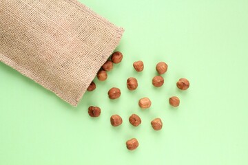 Hazelnut on jute eco canvas bag on green background. Healthy eating diet, nutrition, vegan concept. Protein organic food. Dry snack. National nut day. Copy space for text