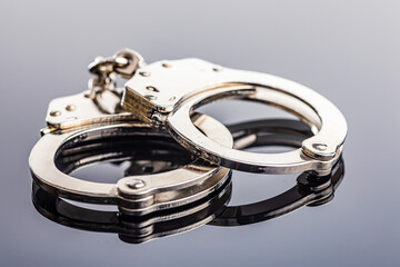 Shiny metal handcuffs on mirror table.