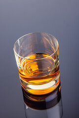 Glass of whiskey or other alcohol on mirror table.
