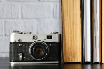 Vintage camera and books on table on light background, close up