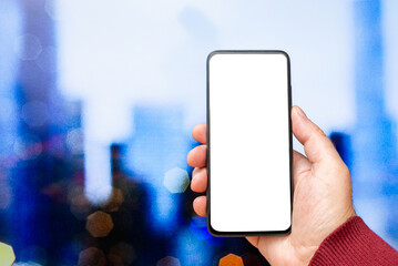 A business man hand holding mockup blank empty phone screen on blurred modern city building landscape background.