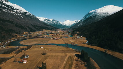 Aerial view of small village in valley with mountains and river.
