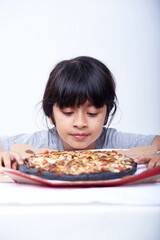 Cute little girl is holding a black pizza on a white background