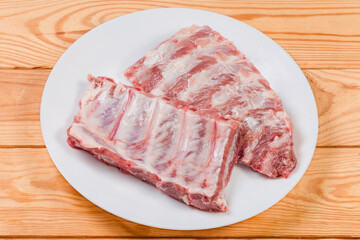 Raw pork ribs on white dish on a rustic table