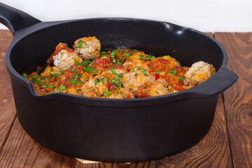 Stewed rice meatballs in deep frying pan, side view