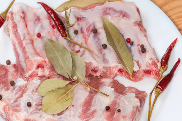 Raw pork ribs with dried spices on dish, top view