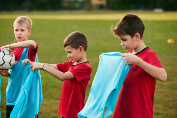 Boy soccer player wearing blue sport uniform on match on football field in motion. Playing football. Children's team games.