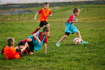 Obraz premium Competitive little players running wearing sport uniform in jersey and cleats. Kids play football on soccer field. Children's school team.