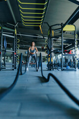 Inside a bustling health club, including young adult, engages in an intensive rope workout session, displaying their dedication to a healthy lifestyle. vertical shot