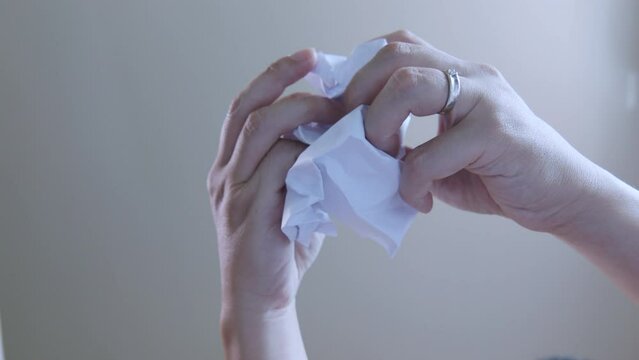 Looking up view, inside trash bin, focuses on person's hand, unfolding piece of paper scribbled with ideas, possibly signifying a mistake idea, and brings the concept of reuse for a circular economy.