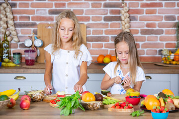 Two little girls in the kitchen with fresh vegetables. Healthy food concept. Happy sisters.