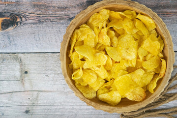 Rustic Delight: Golden Potato Chips in a Wooden Bowl - Tempting and Crunchy Snack on a Textured Background. Potato chips in a wooden bowl with isolated background.
