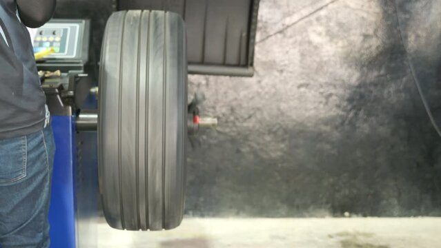 Auto mechanic balancing wheel places weights on steel rim with machine balancer at car service, Seasonal tire change fixing problems replacing broken parts
