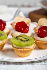 Fruit tartlets. Strawberry, banana and kiwi tartlets on a plate. snack sweet food. Close up