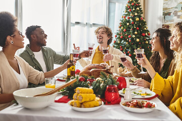 big multiracial family laughing and gesturing while enjoying wine and festive lunch, Christmas