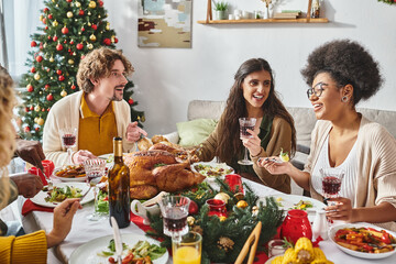 cheerful multiracial family members sitting at festive table and talking lively, Christmas