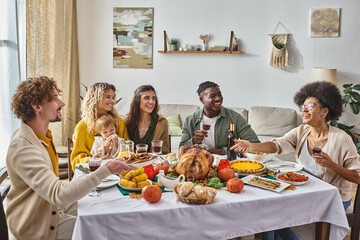 happy man passing plate with roasted potatoes to african american woman during Thanksgiving dinner