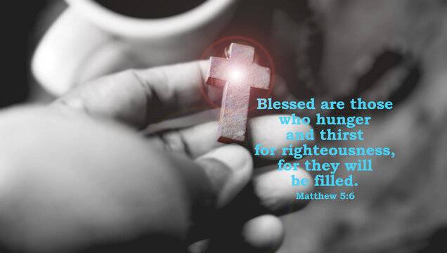 Bible verse quote - In Matthew 5:6, Jesus says, Blessed are those who hunger and thirst for righteousness, for they will be filled. With light on wooden holy cross in hand, in black and white.