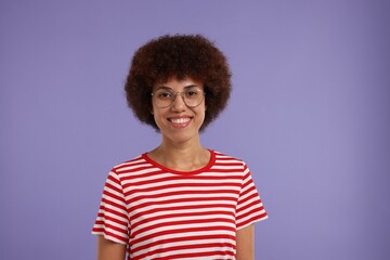 Portrait of happy young woman in eyeglasses on purple background. Space for text