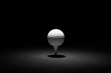 Golf Ball Spotlit on a Black and Gun-Metal Background. A Moody Studio Shot, Casting Shadows