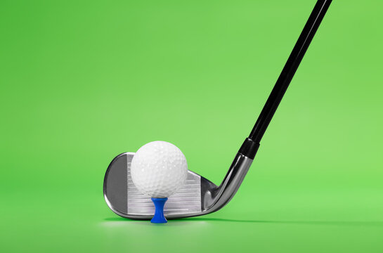Golf Club Iron with Ball on a Blue Tee, photographed on a Green Background with copy space