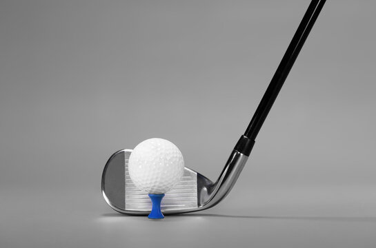 Golf Club Iron and Ball on a Blue Tee, photographed on a Lush Grey Background with Copy Space