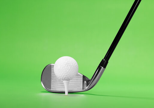 Golf Fairway Iron with a Golf Ball on White Tee, isolated on a Green Background